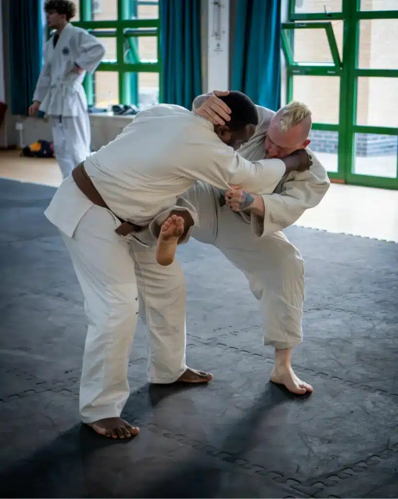 Two jujutsu students in gis gripping each other while practising a throw
