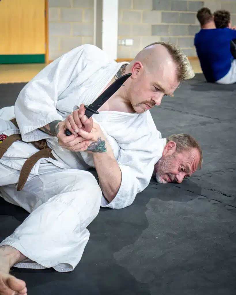 Student finishing a knife defence by pinning the attacker on the mat with an arm lock