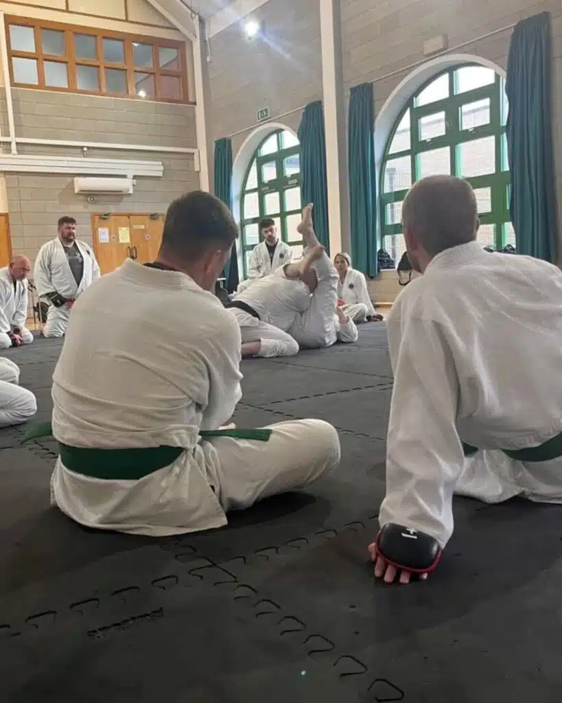 Students in gis sitting on the mat between rounds of groundwork training