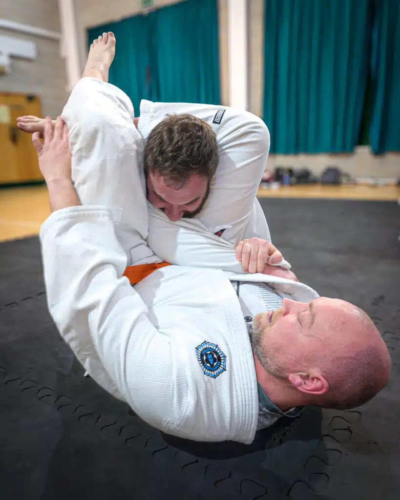Jujutsu student in a gi applying a triangle choke from the bottom