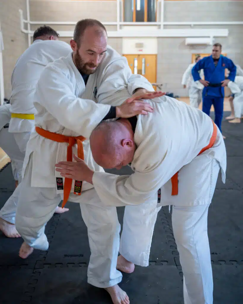 Orange belt students practising a standing headlock escape